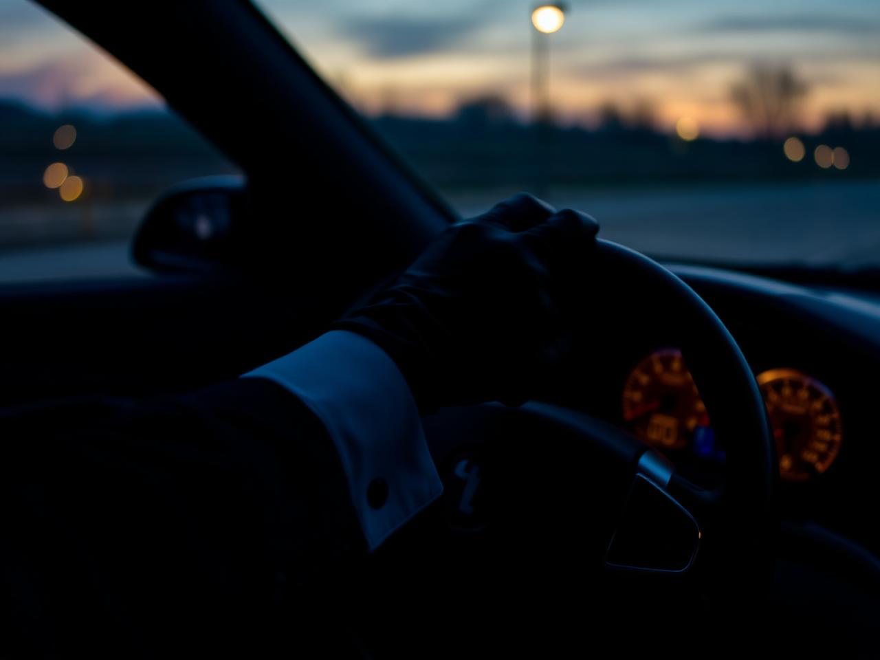 Professional chauffeur at the wheel at dusk