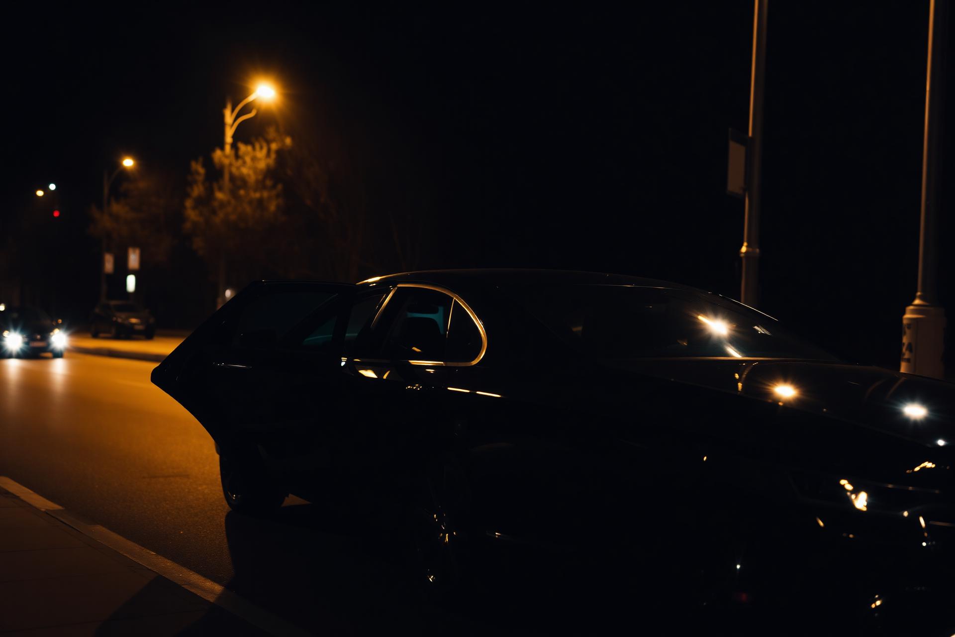Chauffeur opening door of luxury black sedan at night